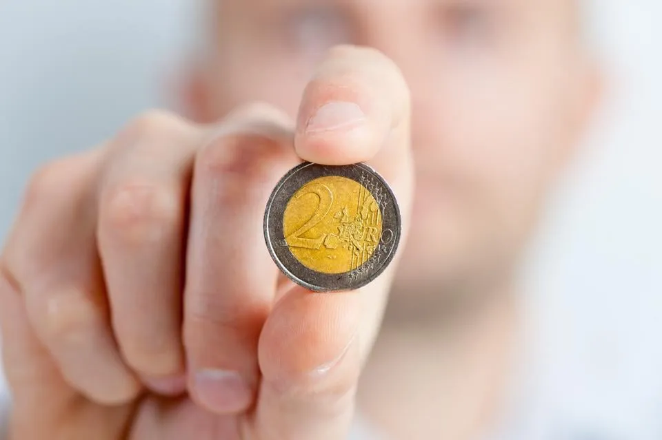 A hand holding up a two euro coin