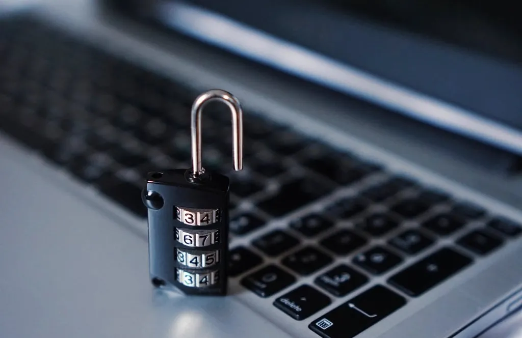 An open combination padlock standing on a laptop keyboard