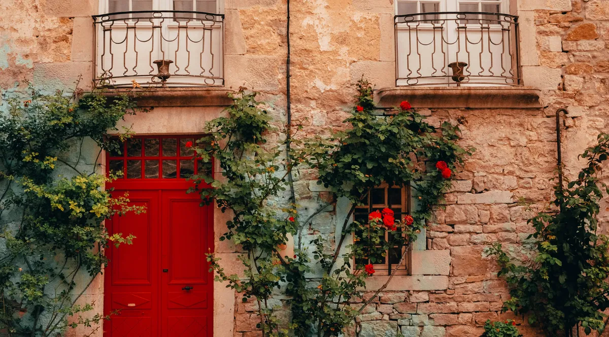 A red door and window in a stone wall