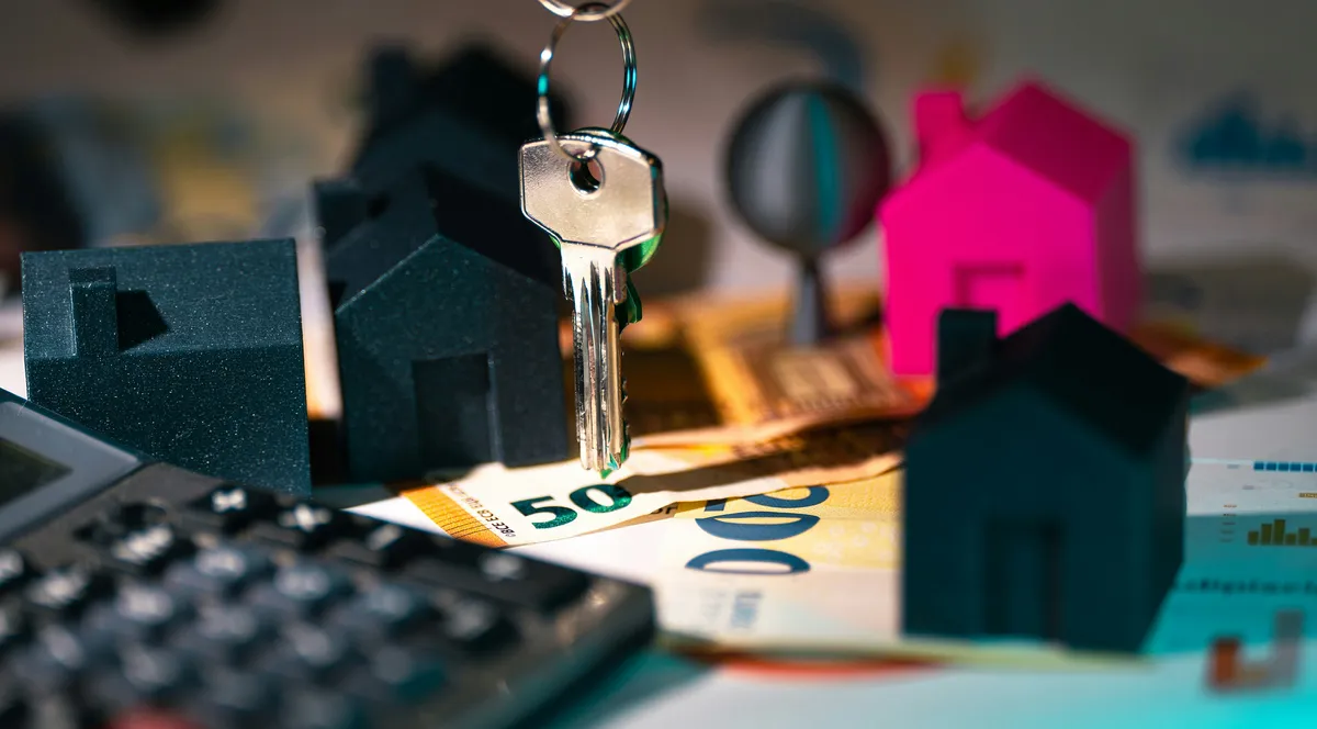 A calculator, a set of keys and a small house model on a table