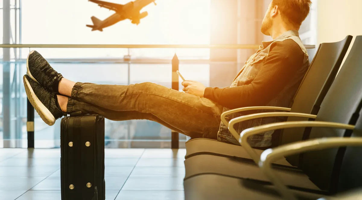 A traveler with a suitcase watching a plane take off