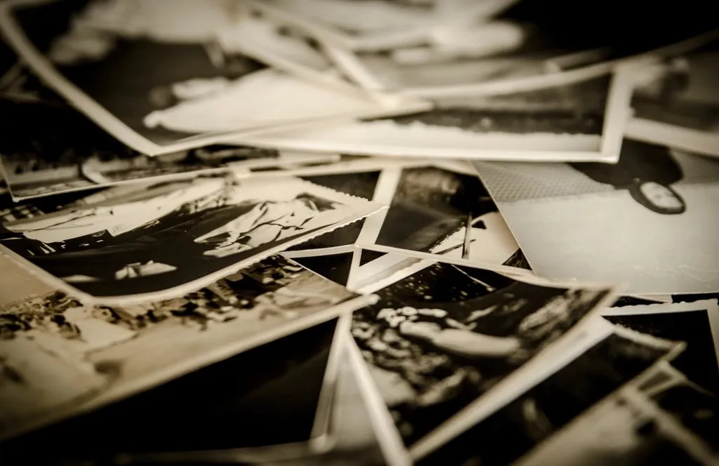 A scattered pile of old black-and-white photographs