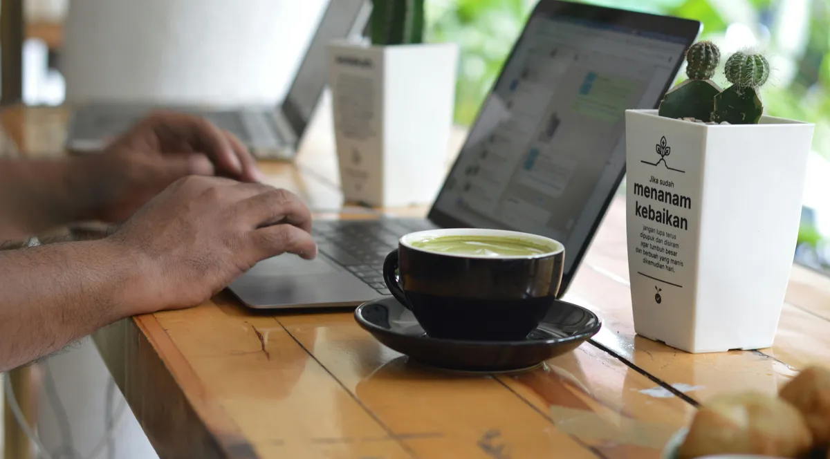 A person working on a laptop next to a cup of tea