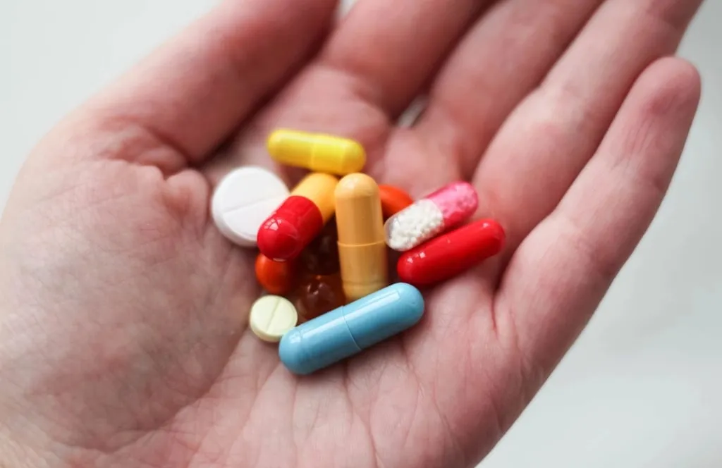 An open hand holding colorful capsules and tablets