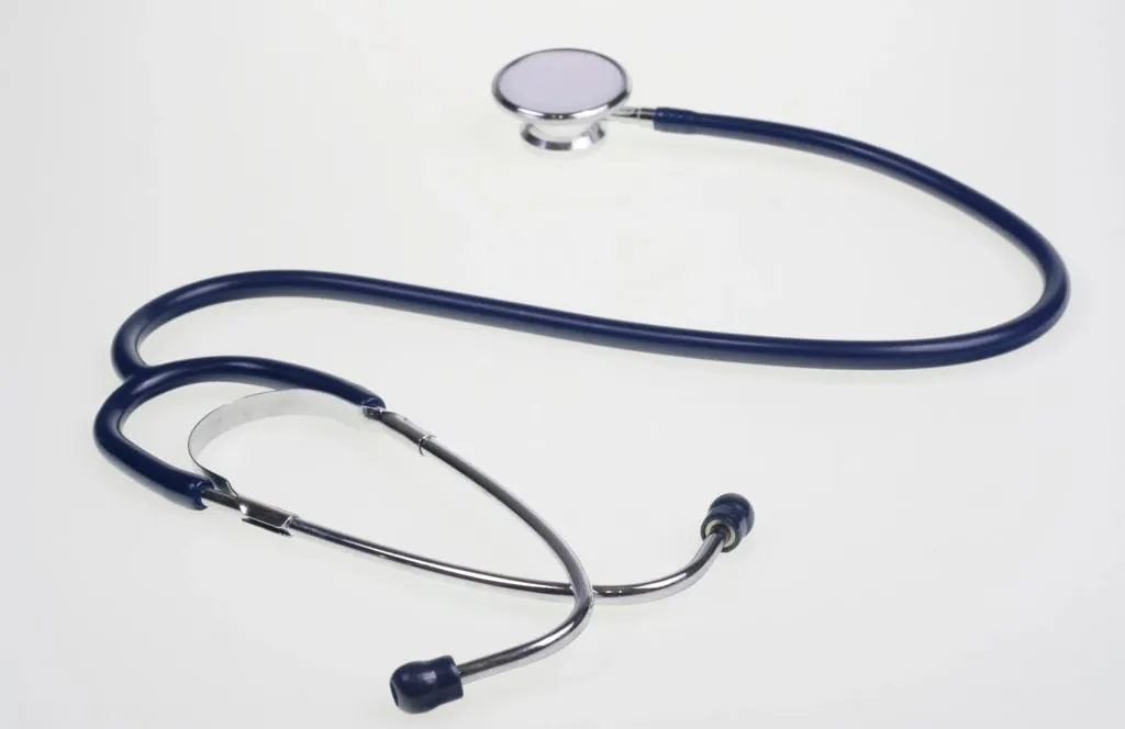 A dark blue stethoscope lying on a white surface