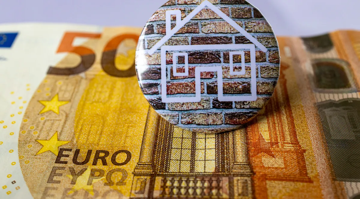 A house badge resting on a 50 euro banknote