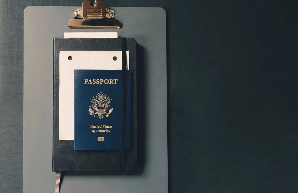 A U.S. passport tucked into a black notebook on a gray clipboard
