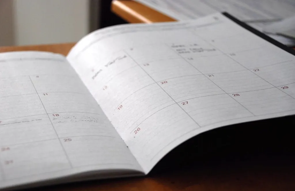 An open month planner on a wooden desk, with a few handwritten notes