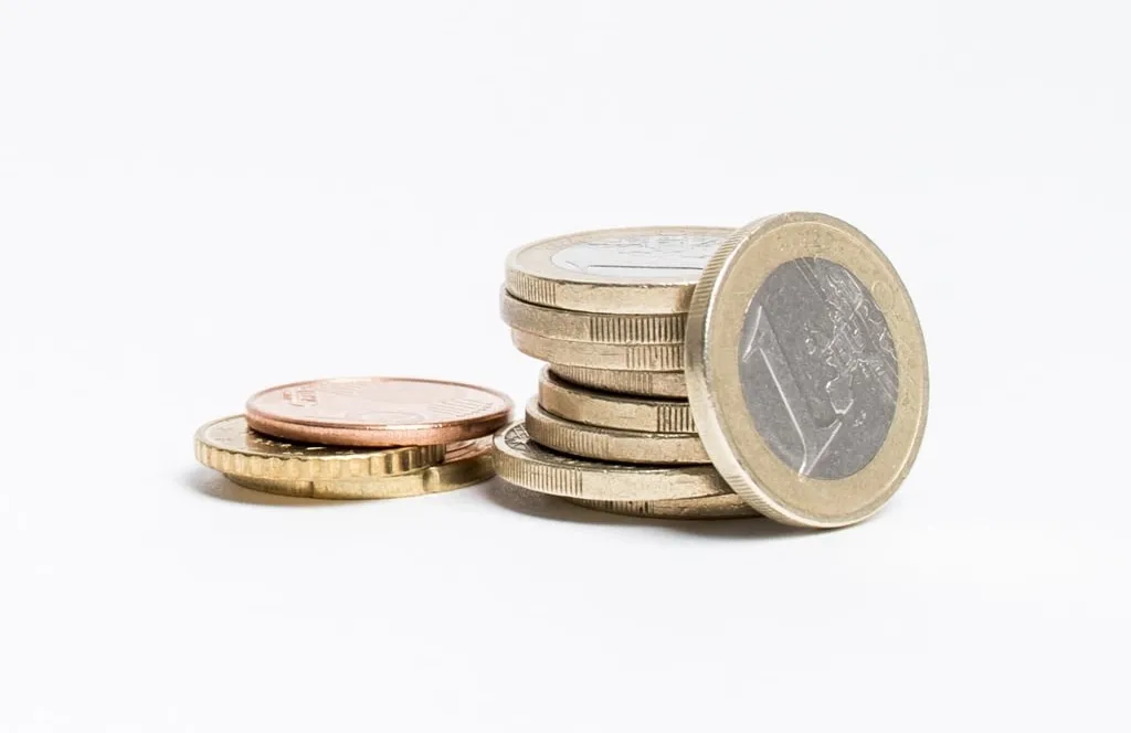 A small stack of euro coins and cent coins on a white surface