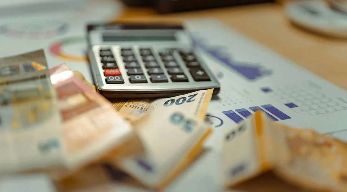 A calculator on top of a pile of dollar bills