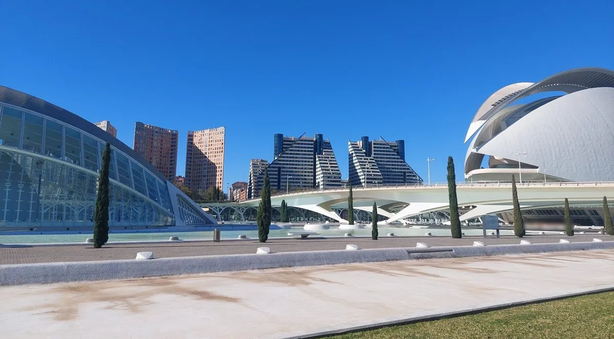 Residential towers behind the white curves of Valencia's City of Arts and Sciences under a clear blue sky