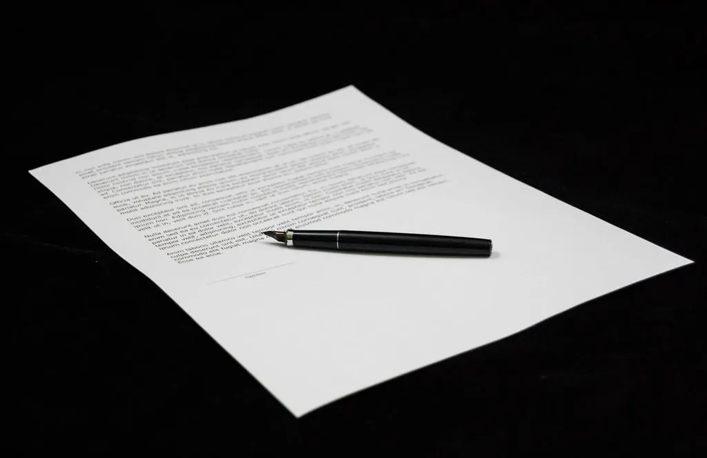 A pen resting on a signed legal document on a wooden desk